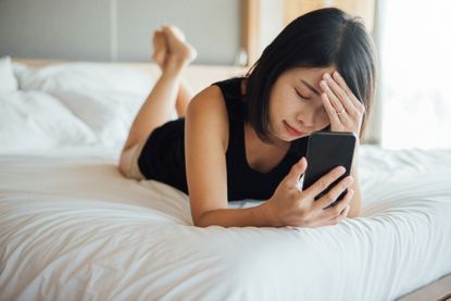 Vaginal dryness treatment: Young Woman Feeling Frustrated While Using Smart Phone On Bed