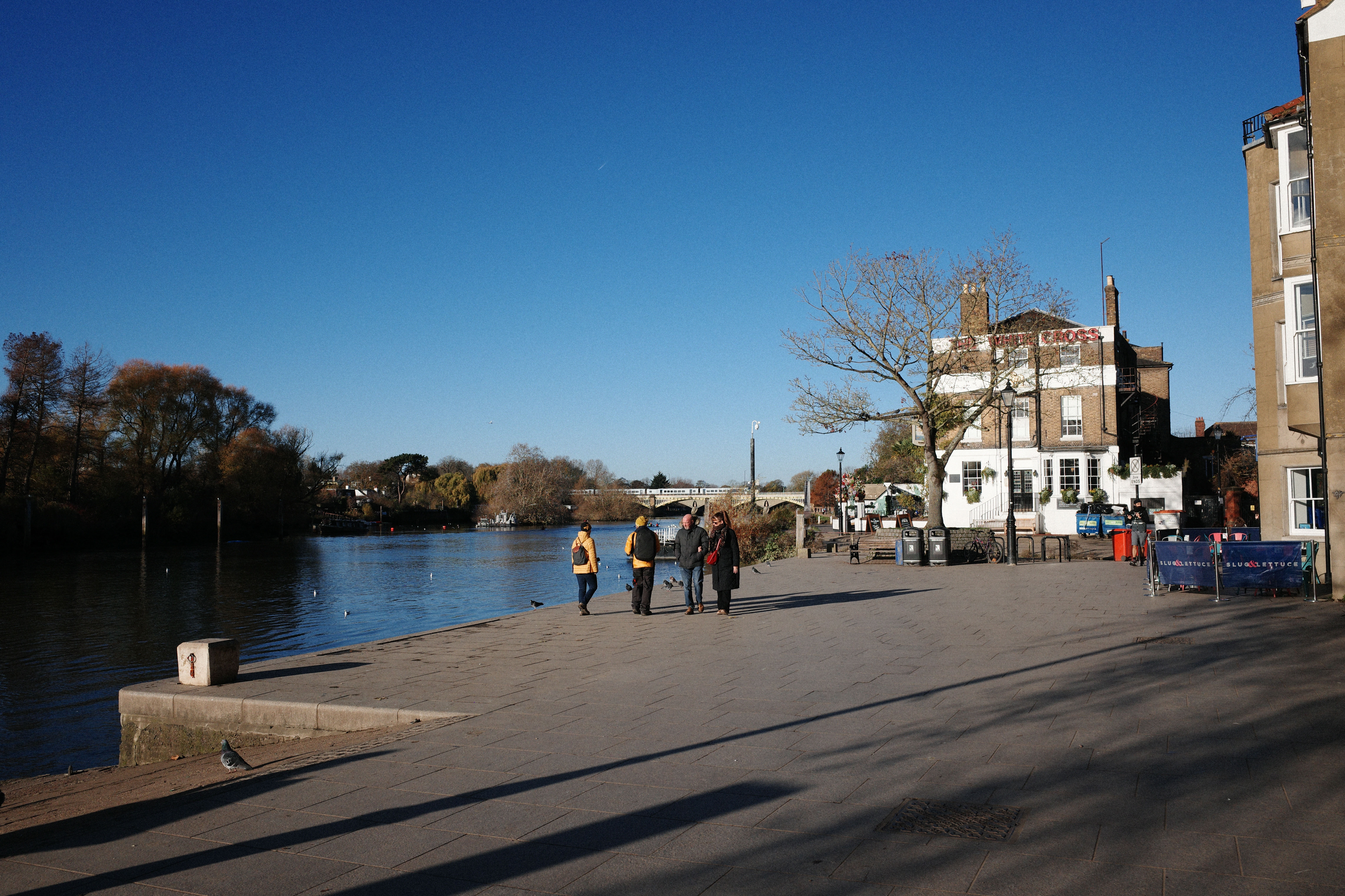 View of a river and adjacent path with a large pub in the background
