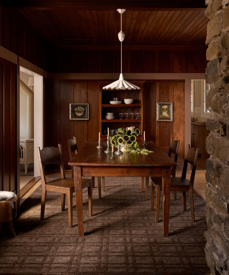 a wood-paneled dining room with a large wood table and chairs and a brown rug