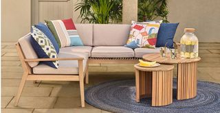 Wooden garden corner sofa with cream cushions and round wooden coffee tables