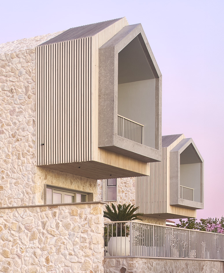 views of Pur residential recording studio, a family of structures in a cluster, made of stone and wood against blue mediterranean skies