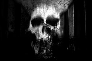 Spooky blurry image of a skull against a black background. 