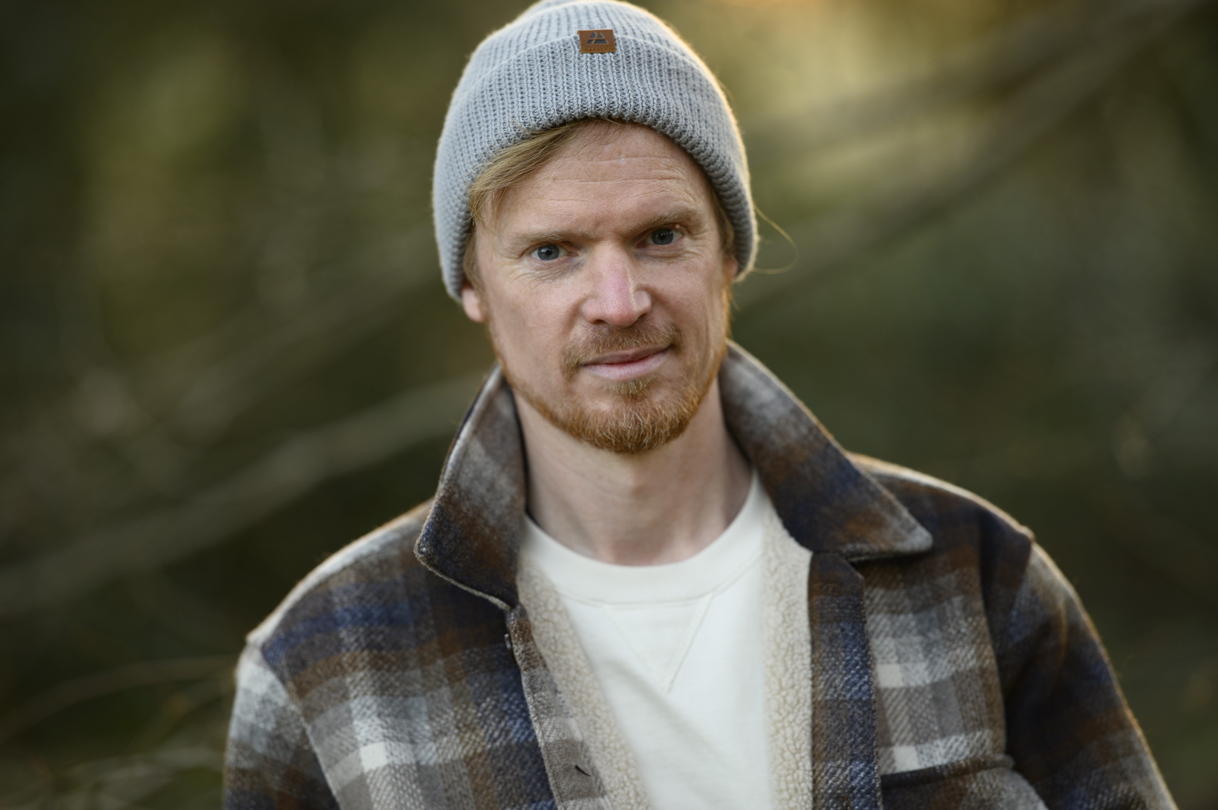 Portraits of a man in a beanie hat and shacket at golden hour with dappled light in background