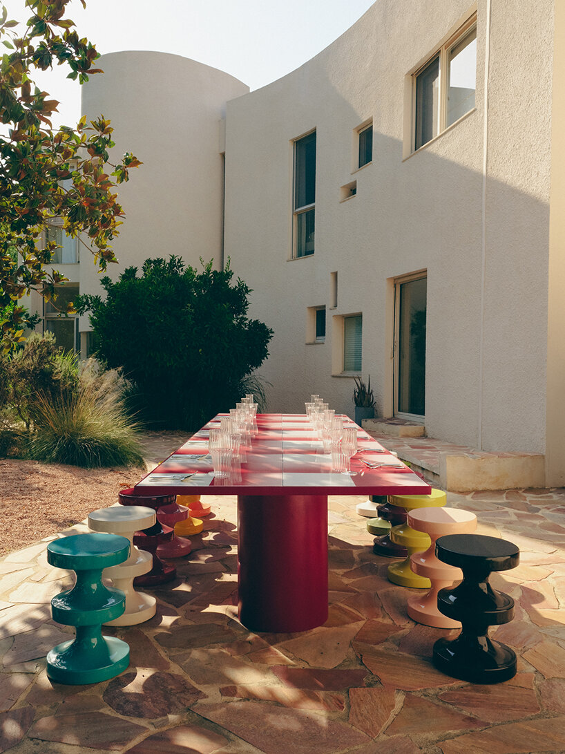 A colorful, geometrical table with a checkered bordeaux and white surface is styled with whimsical stools in lots of different colors.