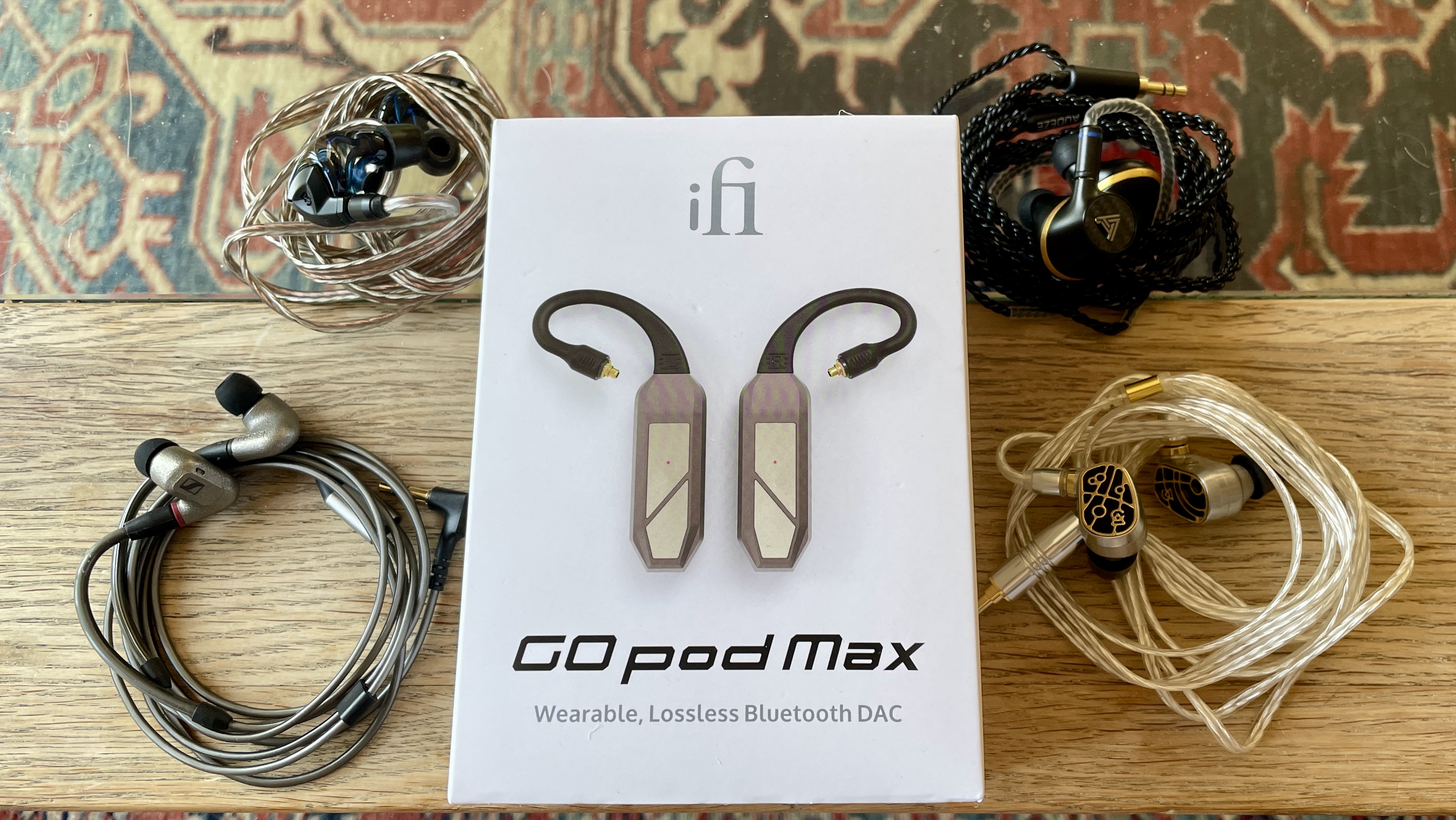 iFi Go Pod in a hand, with high-end wired earbuds and in the case, which accepts even larger earbuds