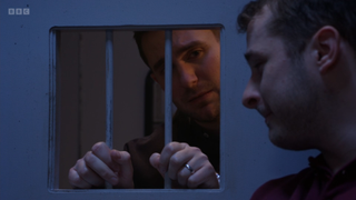 Callum Highway looks at Ben Mitchell through the cell door bars.