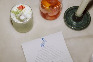 The Blue Pelican menu next to two of the restaurant's cocktails and a green candle holder