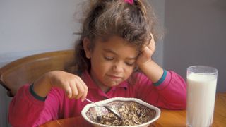 Girl turning nose up at bowl of food