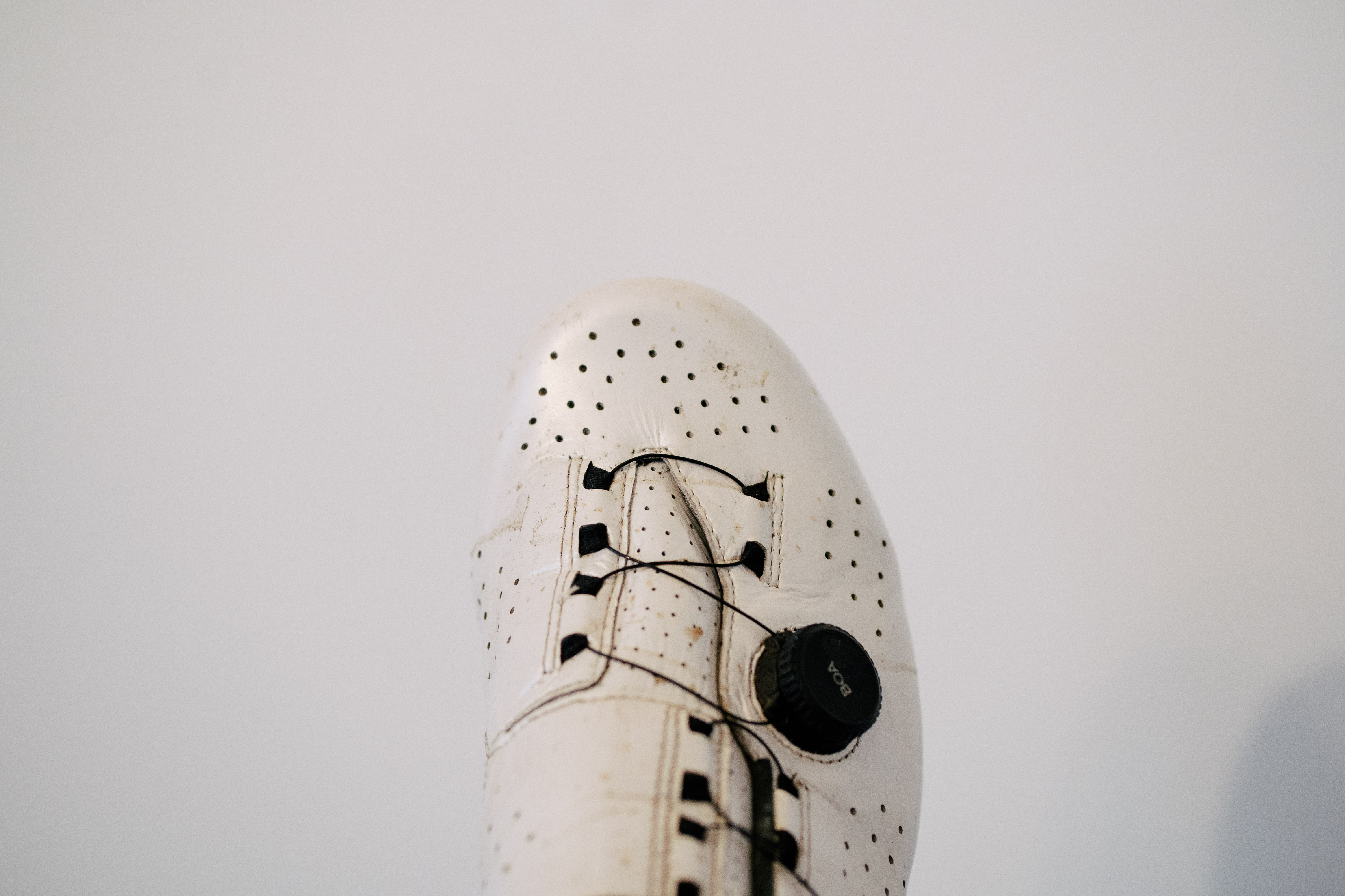 A white leather cycling shoe on a green sofa