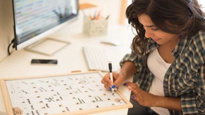 Young woman at her desk writing on whiteboard calendar