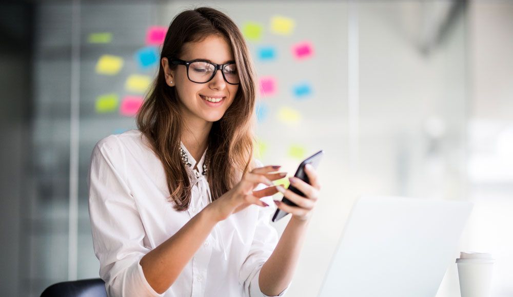 A young woman wearing glasses using a smartphone.