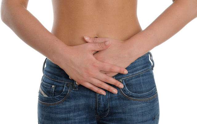 Woman holding her hands in front of bloated stomach
