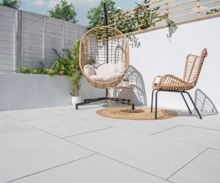 white slabbed patio area with wicker hanging chair