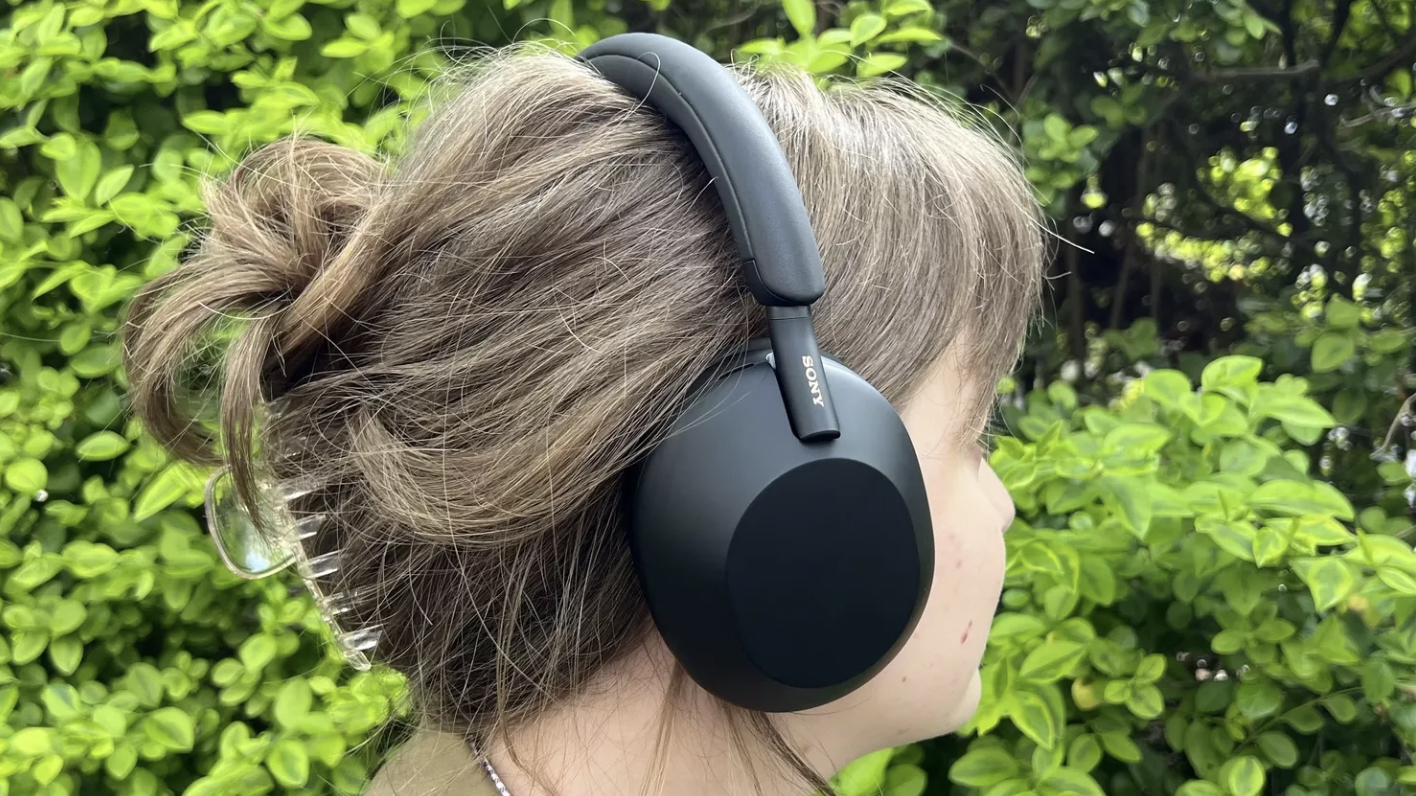 Someone wearing the Sony WH-1000XM5 headphones against a green backdrop
