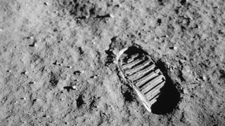 a footprint of a large clunky boot in dusty gray soil