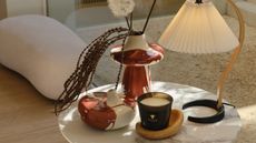 westwing vases on side table with lamp and candle, with boucle ottoman in the background with beige rug