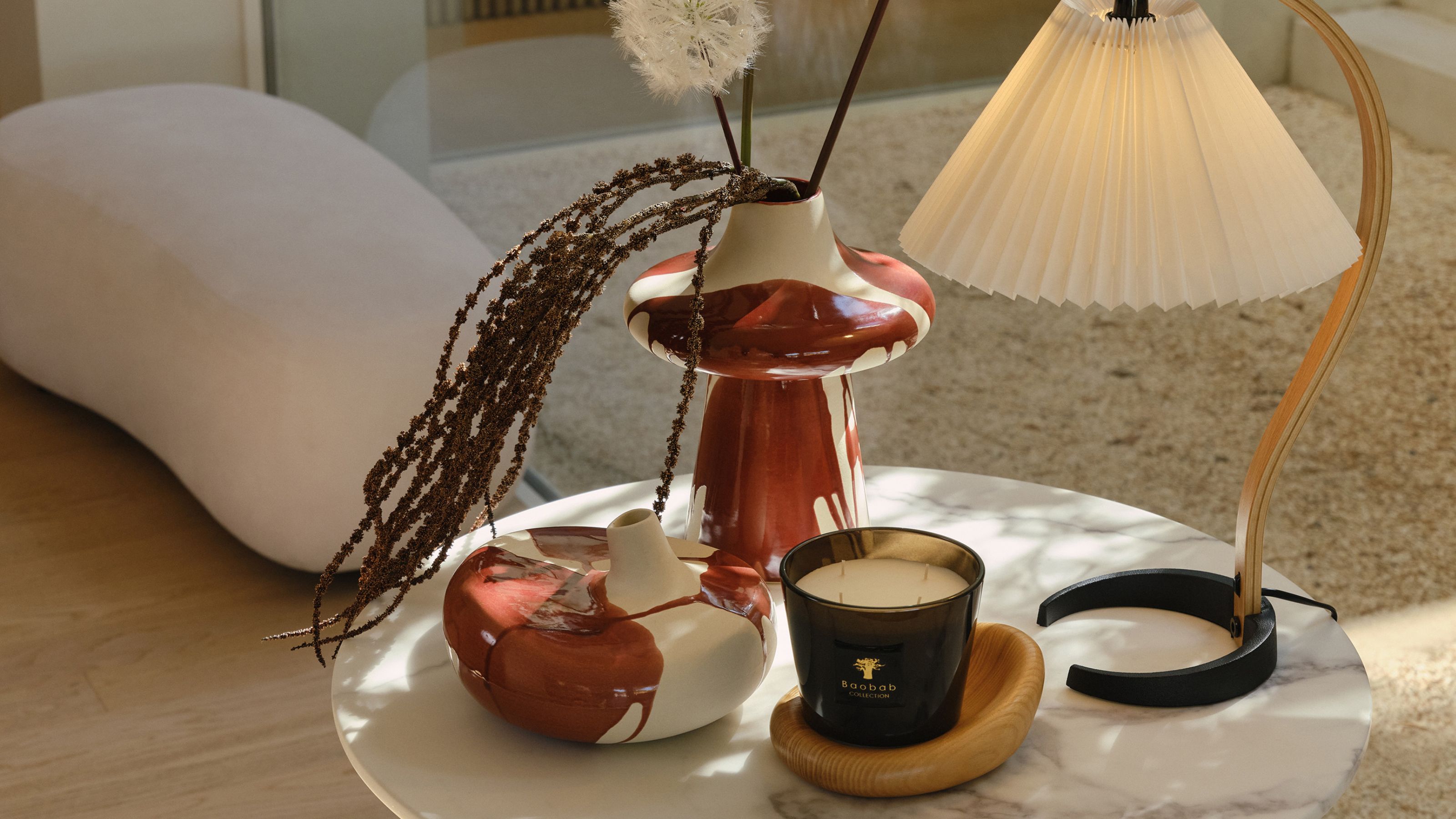 westwing vases on side table with lamp and candle, with boucle ottoman in the background with beige rug