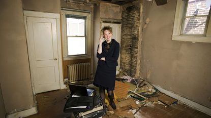 A landlord stands in a run-down house.