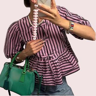 close up of woman wearing pink stripe blouse and green small handbag 