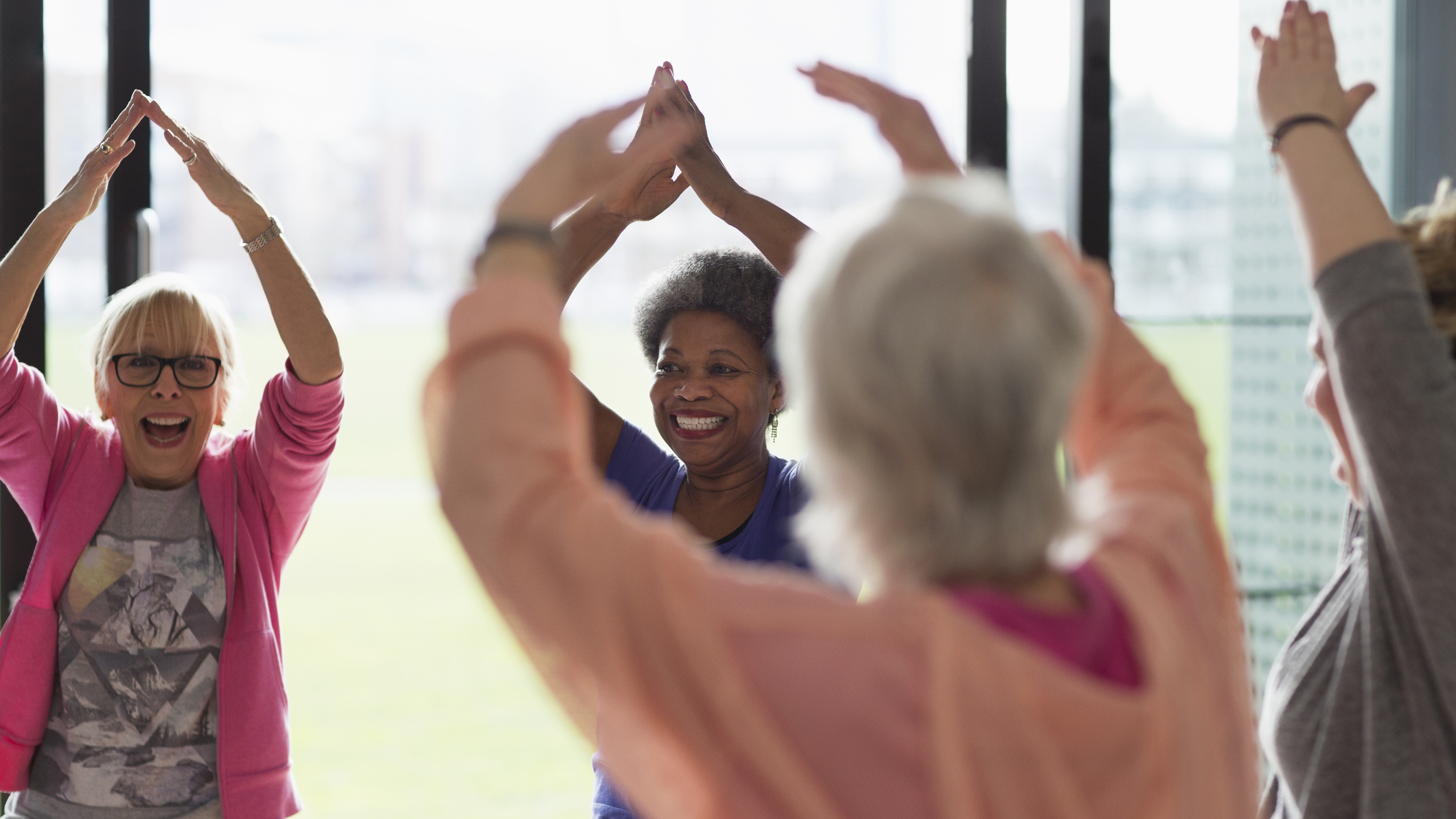 Group of smiling women standing in a circle with their arms raised overhead