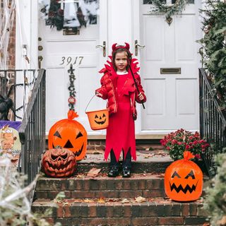 Best Halloween decorations: A young girl in Halloween costume stands by a front door surrounded by Halloween Pumpkin Leaf Bags