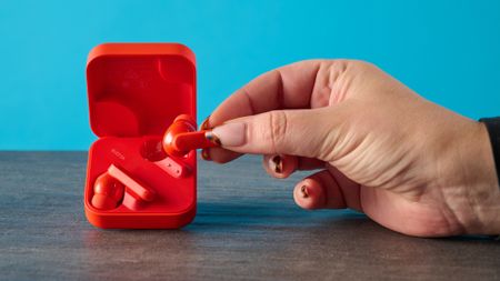 cmf buds 2a in the orange colorway photographed in front of a blue background