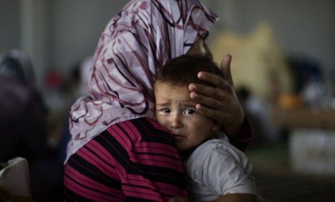 Little Amjad Al-Saleh, whose family fled their home in September, is comforted by his mother after suffering food poisoning. 