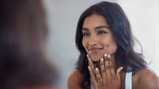 woman looking in the mirror applying face cream