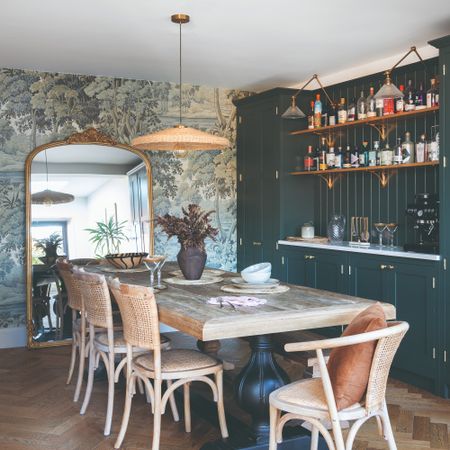 A dining table with a long rectangular dining table, a rattan pendant light and a bar to the side