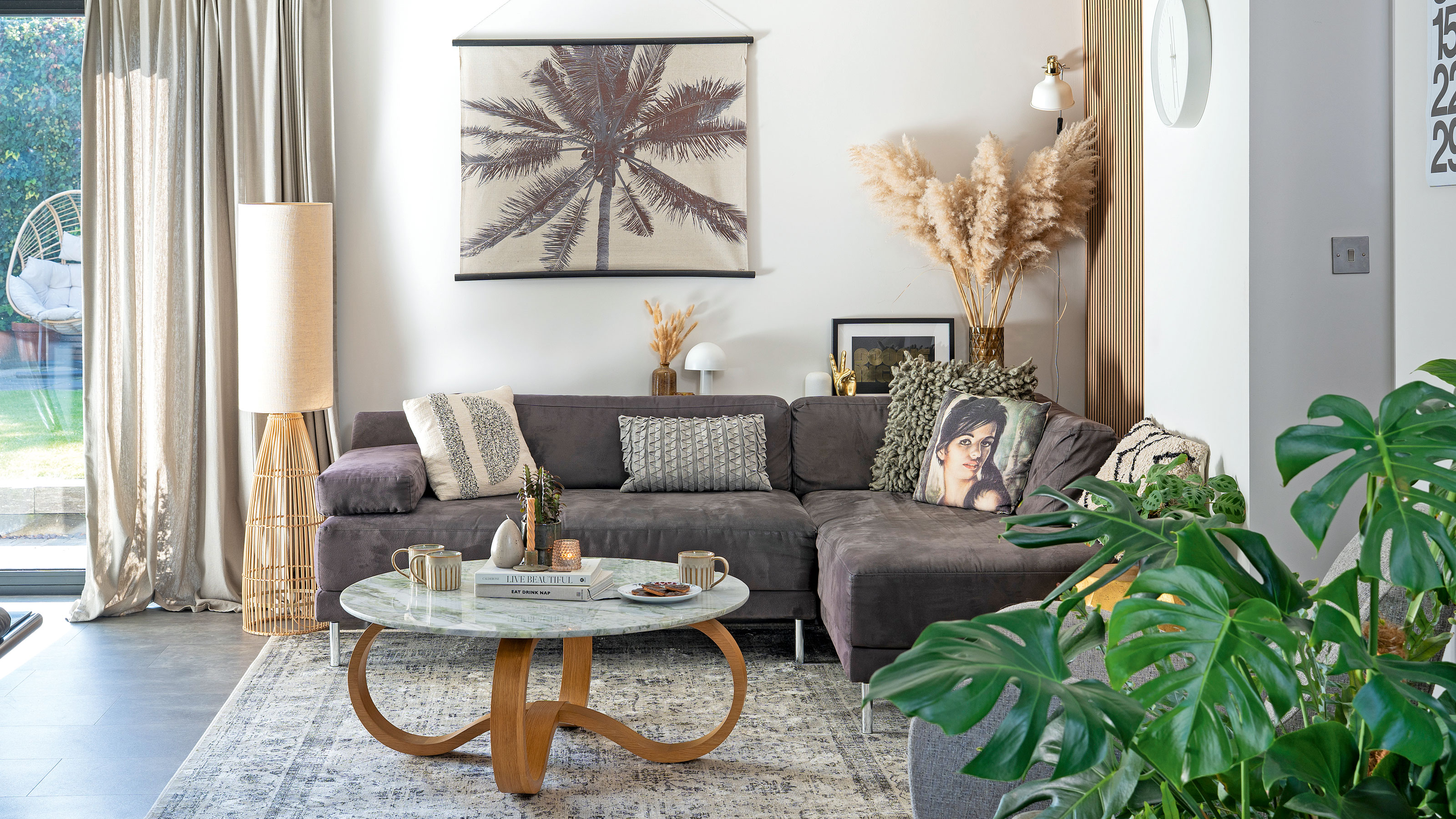 White room with grey sofa, coffee table and rug with palm tree print on wall
