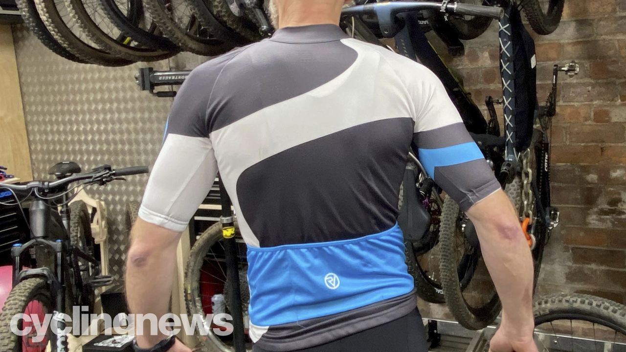 An older white man wearing a blue, black and white Proviz jersey, as seen from the back