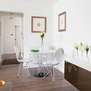 dining space with white wall and wooden floor and dining table and chair