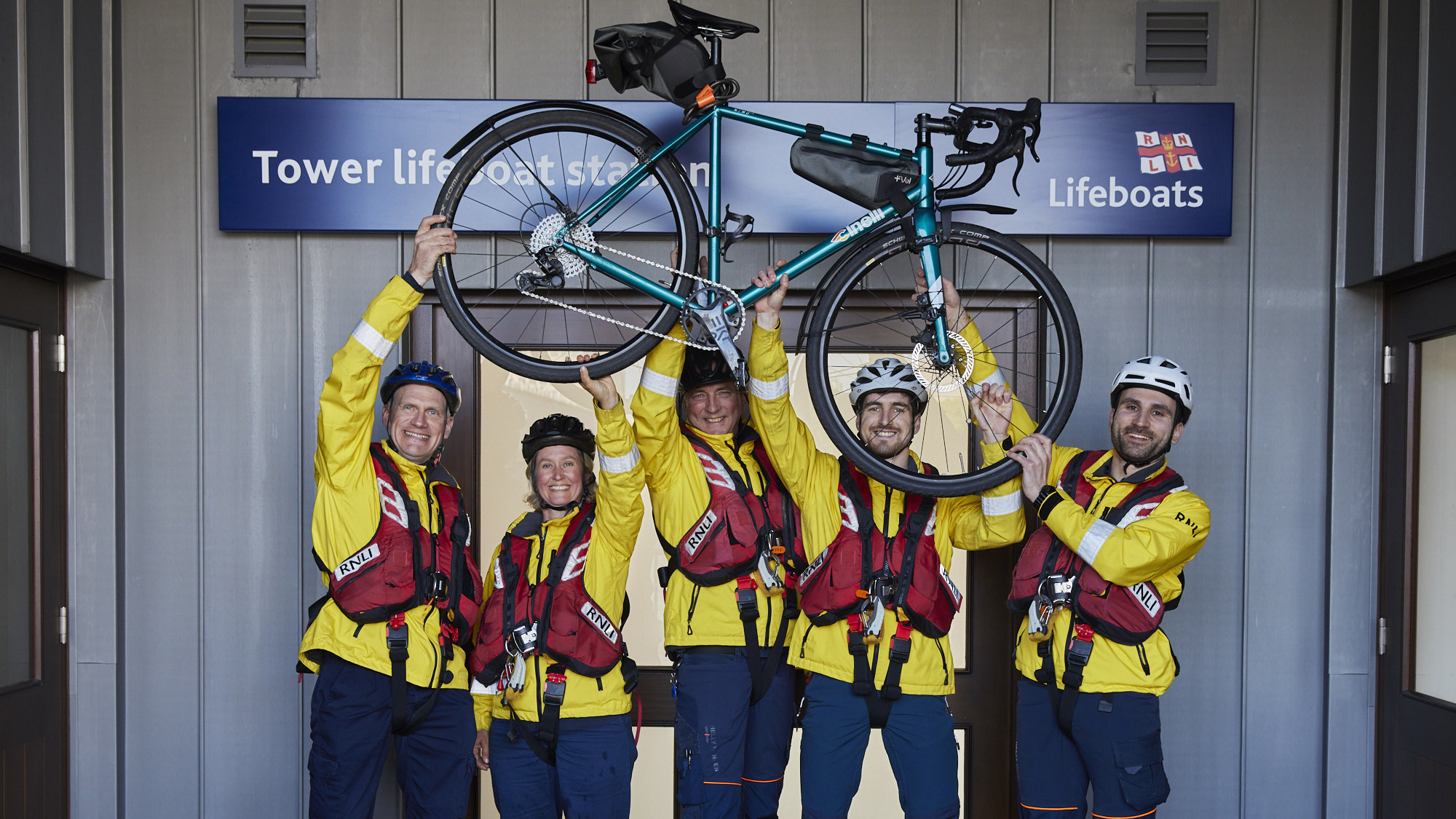Riders from Tower Lifeboat Station pose with a bike ahead of their 540km challenge