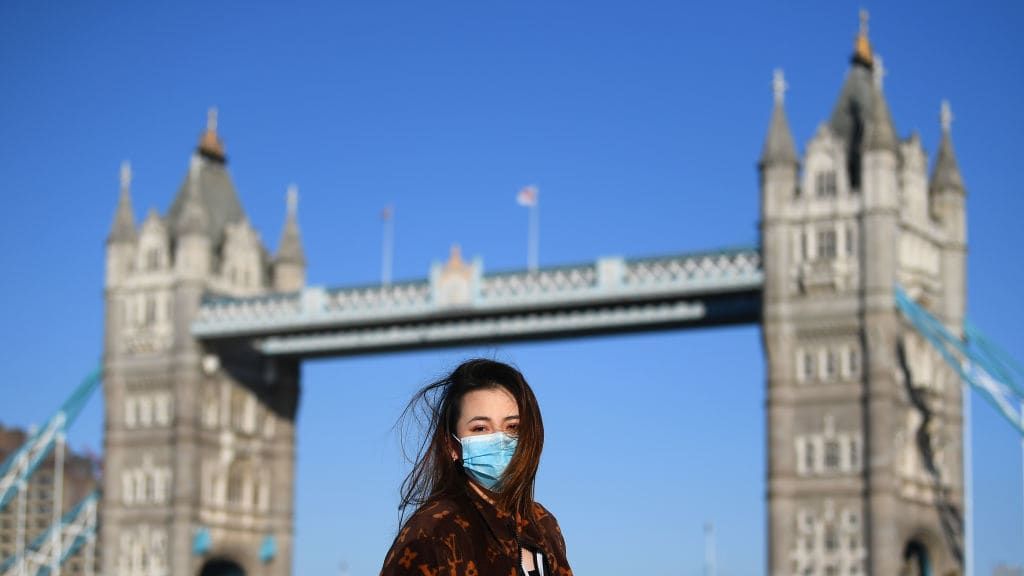 A woman wears a mask by London&amp;#039;s Tower Bridge.