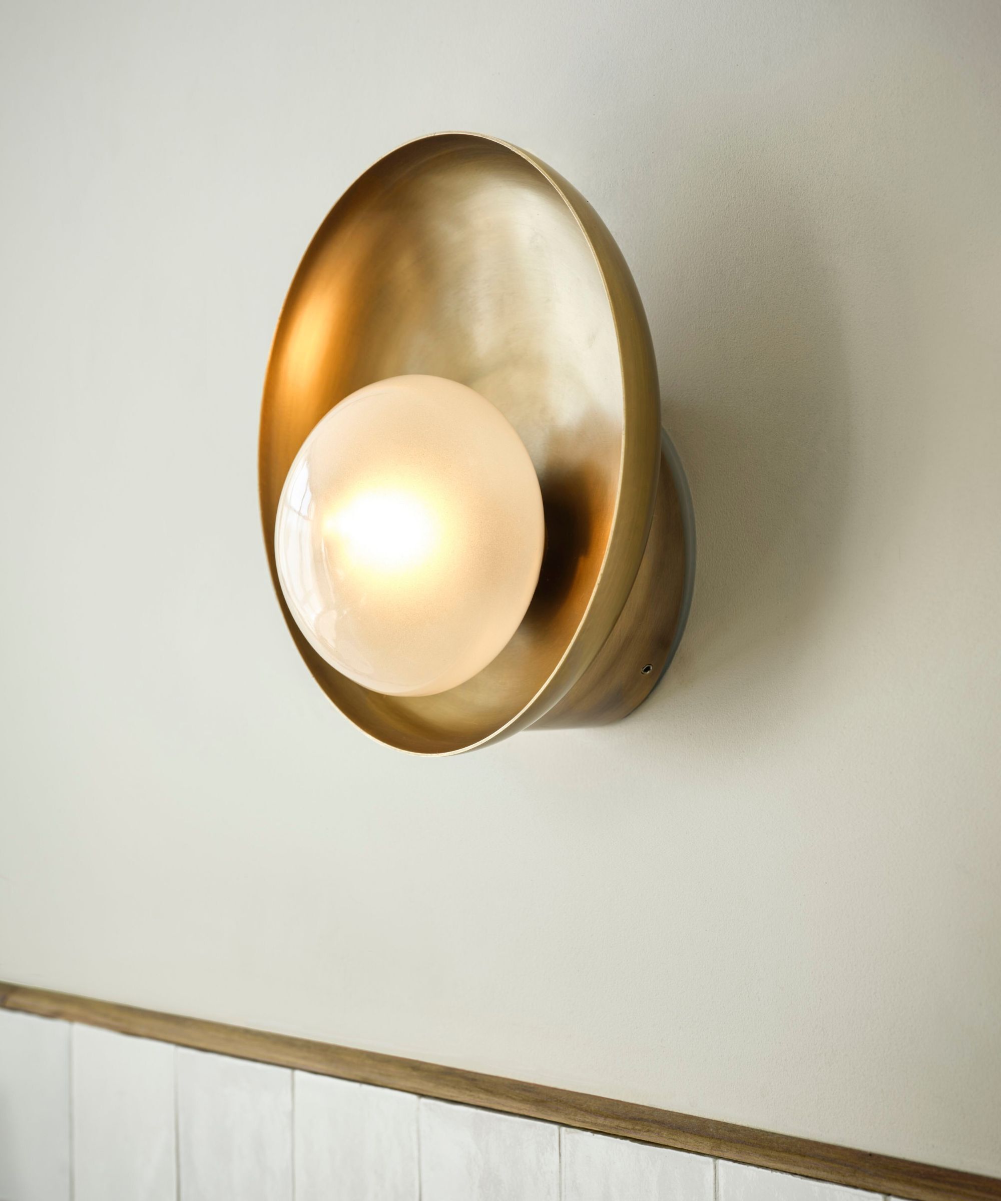 Gold colored bathroom light in an oyster style with a pearlised centre