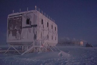 An elevated dorm at NSF's Amundsen-Scott South Pole Station is shown with a new elevated station in the background. The photo was taken on Sept. 9, 2005. The Pole is currently experiencing a period known as civil twilight; the sun will not rise above the horizon until late September.