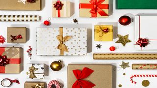  Image shows wrapped presents with rolls of wrapping paper and ribbons