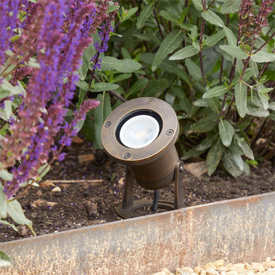 brass uplighter in flowerbed
