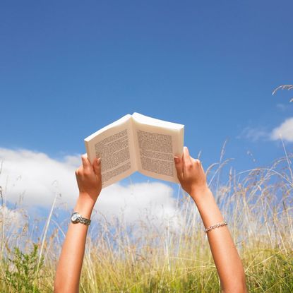 Best self help books UK: A woman reading a book in a field