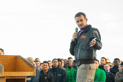 Capt. Brett Crozier, commanding officer of the aircraft carrier USS Theodore Roosevelt (CVN 71), gives remarks during an all-hands call on the ships flight deck Dec. 15, 2019