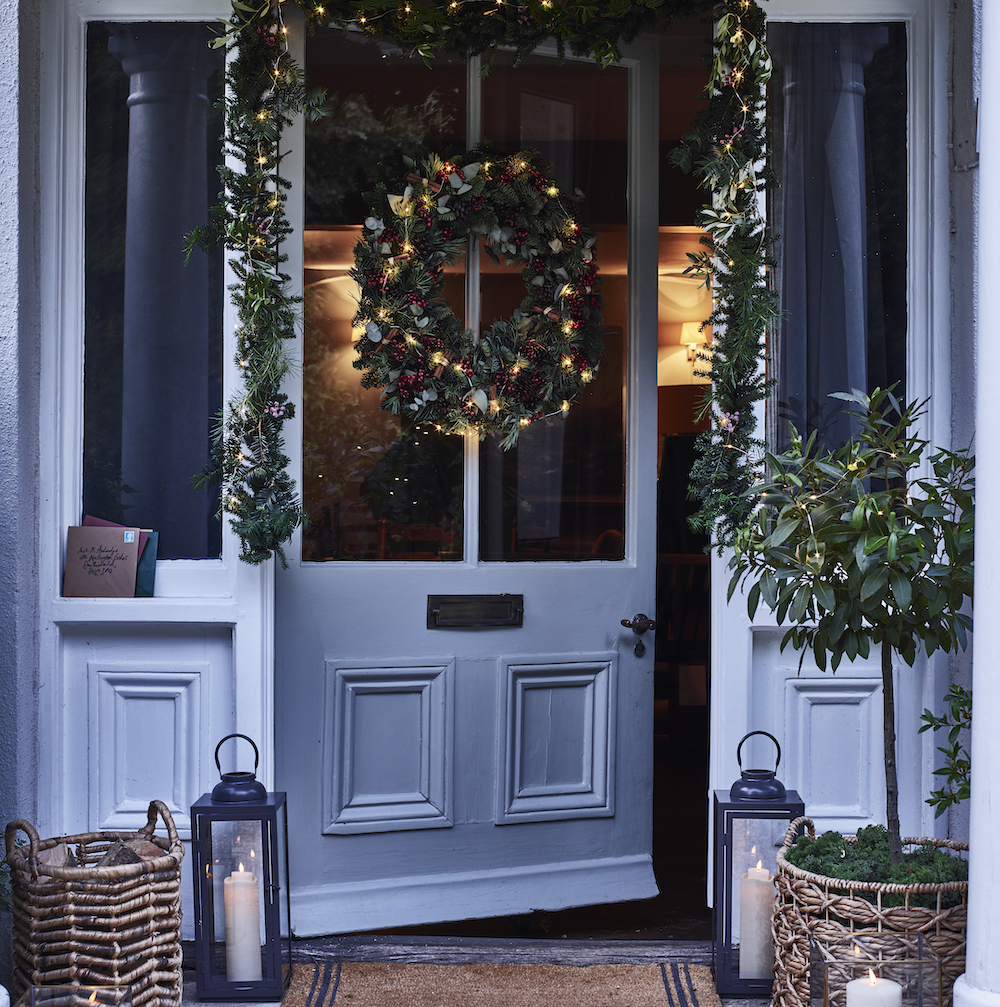 White front door with Christmas Wreath and garland with fairy lights