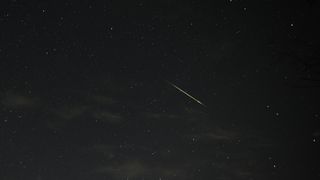a meteor streaks across a starry night sky
