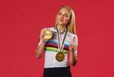 Cat Ferguson wearing two gold medals holding up a finger to gesture she is number one