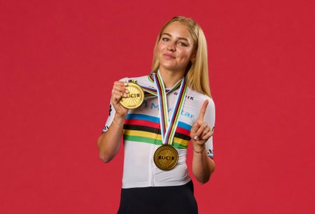 Cat Ferguson wearing two gold medals holding up a finger to gesture she is number one