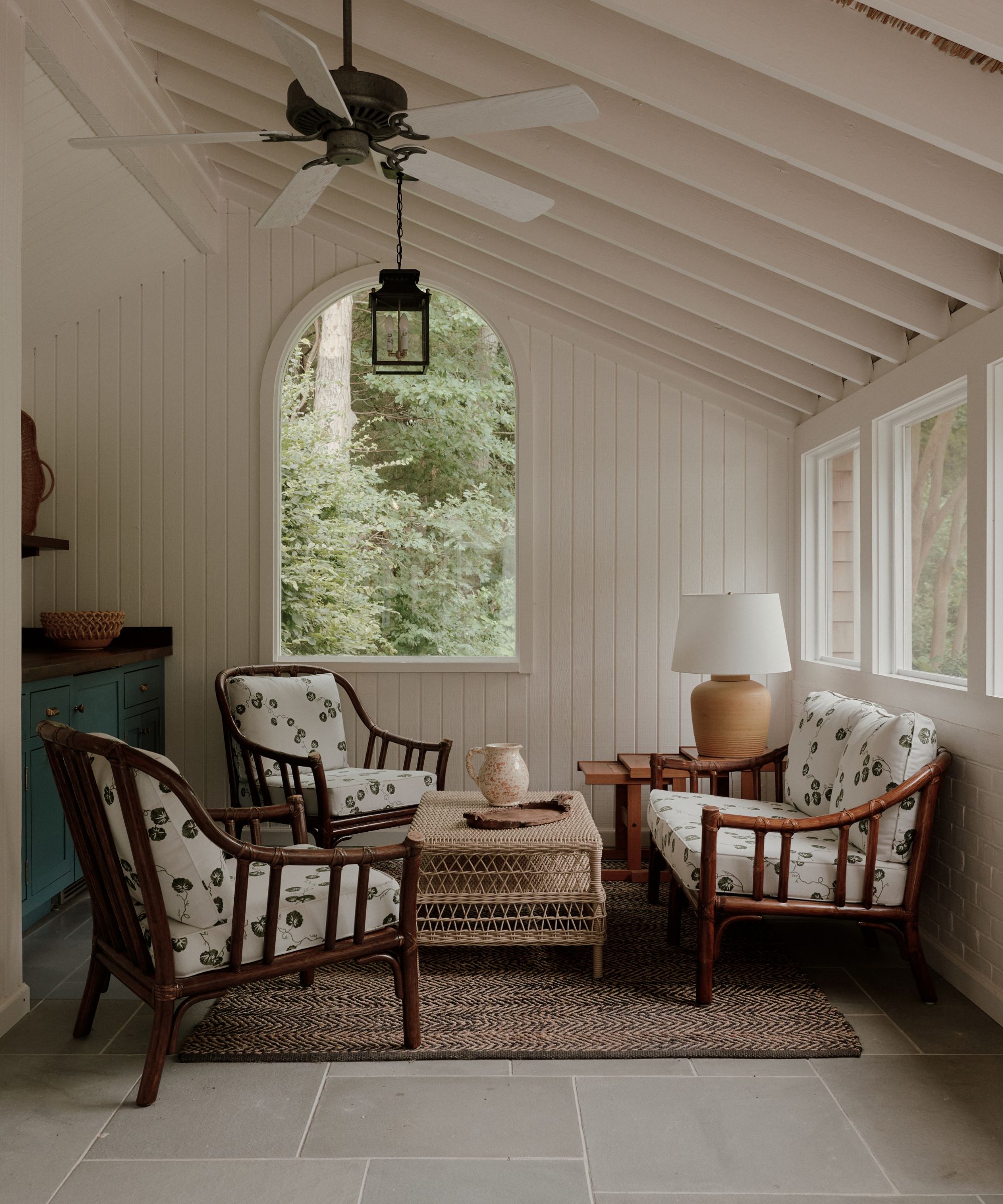 covered porch with bamboo furniture and paneled wall arch window