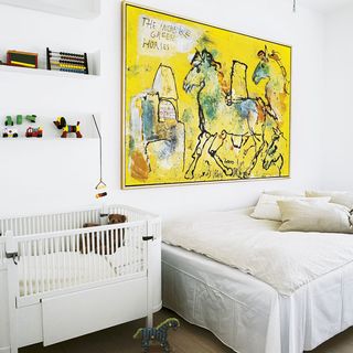 guest bedroom with white wall and paintings on wall with cushions on bed