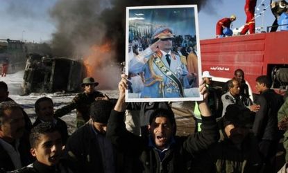 A group of Gadhafi supporters stand in front of a burning truck: The Libyan leader and his loyalists have been put on the defensive, as the rebels move toward the capital, Tripoli.