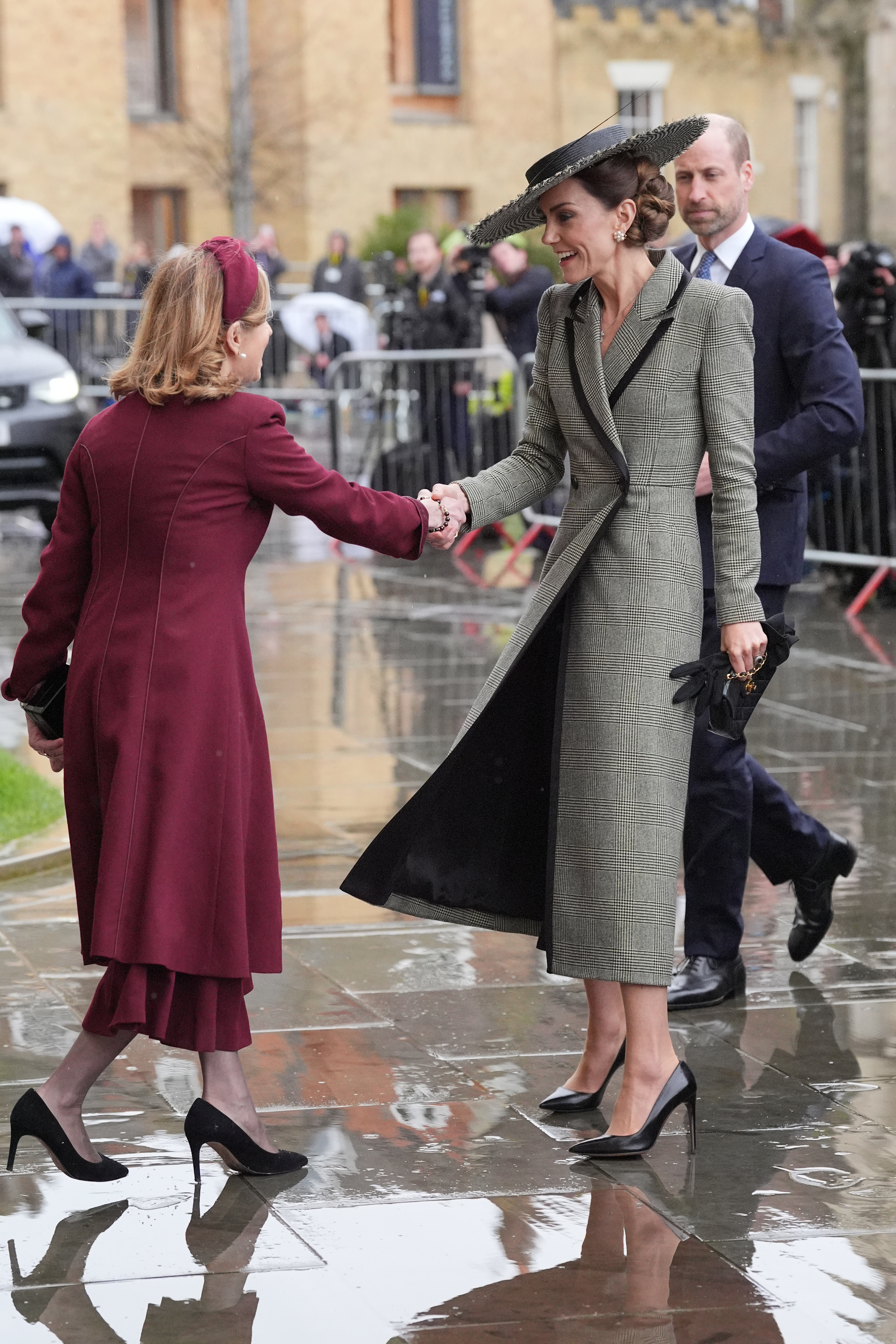 Princess Kate wearing a gray coat shaking hands with a lady