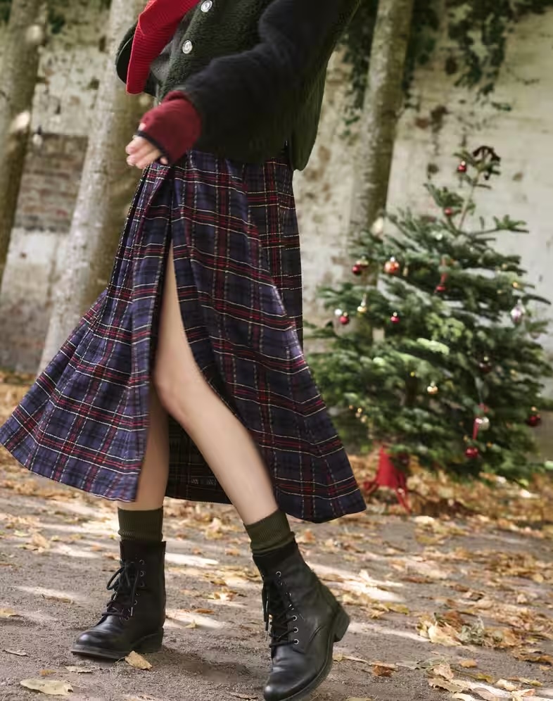 Model in a green jumper and a kilt with high thigh slit