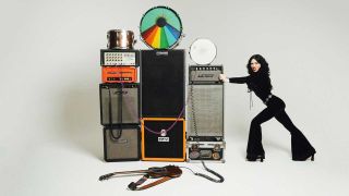 Rosalie Cunningham pushing an amplifier that's part of a pile of vintage musical equipment while grimacing